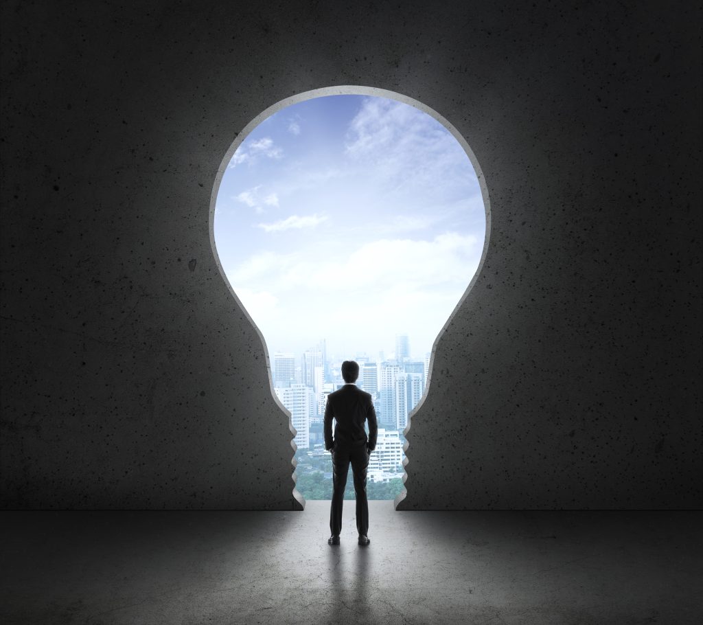 Businessman standing in front of bright big light bulb looking for Operational Excellence