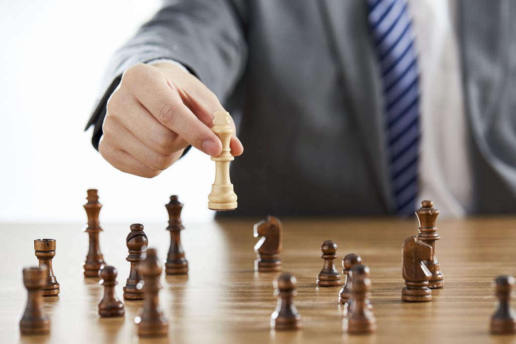 A businessman holding a chess piece representing competitive advantage which is a part of HR outsourcing